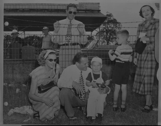 WILBUR SHAW KNEELS with his wife and son as Tony Hulman stands 1949