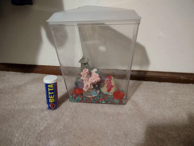 Small corner fish tank with rocks and decorations and beta fish food
