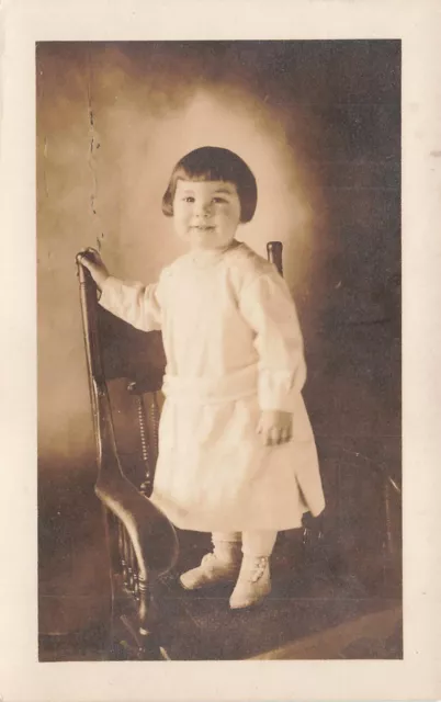 VINTAGE RPPC REAL  PHOTO POSTCARD CUTE SMILING LITTLE GIRL ON CHAIR c1910 042824