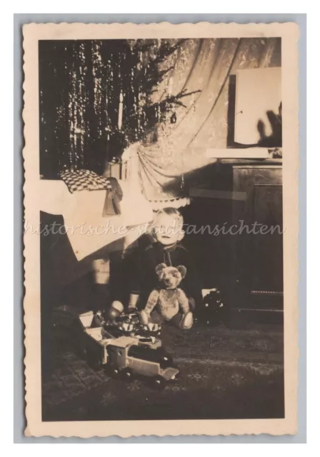 Junge mit Teddybär und Spielzeugeisenbahn an Weihnachten - Altes Foto 1930er