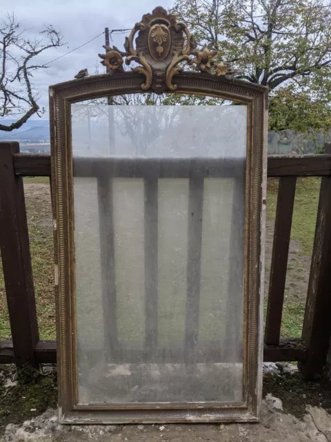 Cadre de miroir en bois et stuc doré à décor de fleurs et coquille.