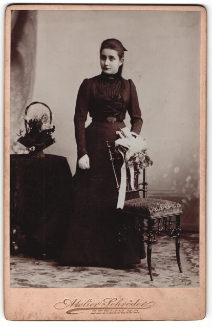 Fotografie Atelier Schröder, Berlin, Junge Frau in dunklem Kleid steht mit eine