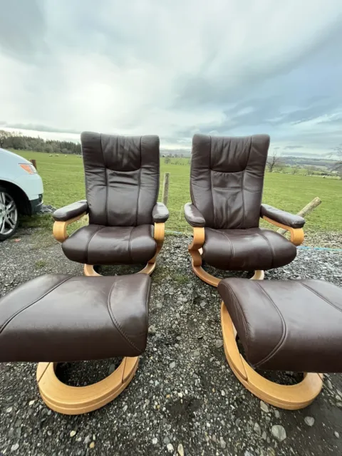 A Matching Pair Of Himolla Brown Leather Reclining Armchairs And Footstools
