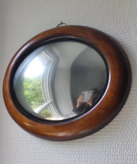 Miroir de sorcière ovale en bois teinté.