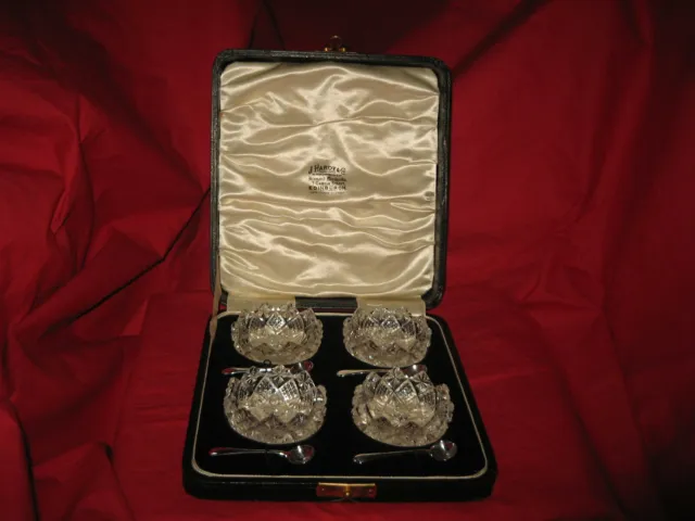 Ein Set mit vier einzelnen durchsichtigen Glas offenen Salzkellern mit 4 silbernen Löffeln
