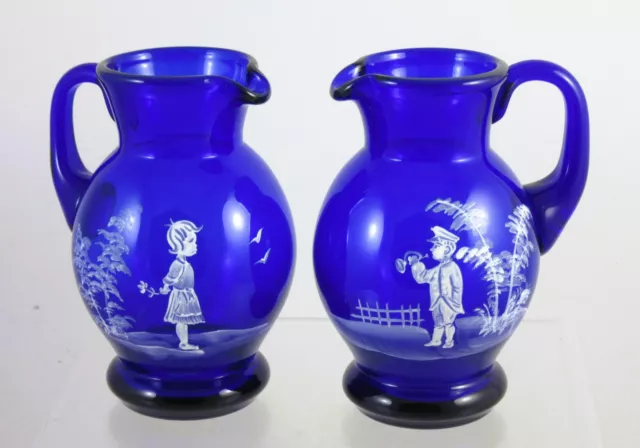 Bohemian blue glass 'Mary Gregory' style jugs  x 2 - boy and girl