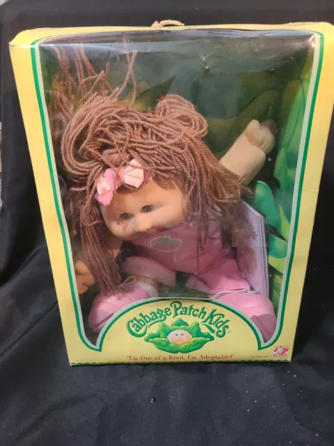 2004 cabbage patch kid in the box with papers, brown hair & eyes, pink bibs