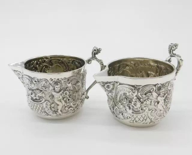 Pair Victorian Sterling Silver Cupid, Floral, Mythic Cream Jugs Antique 1900
