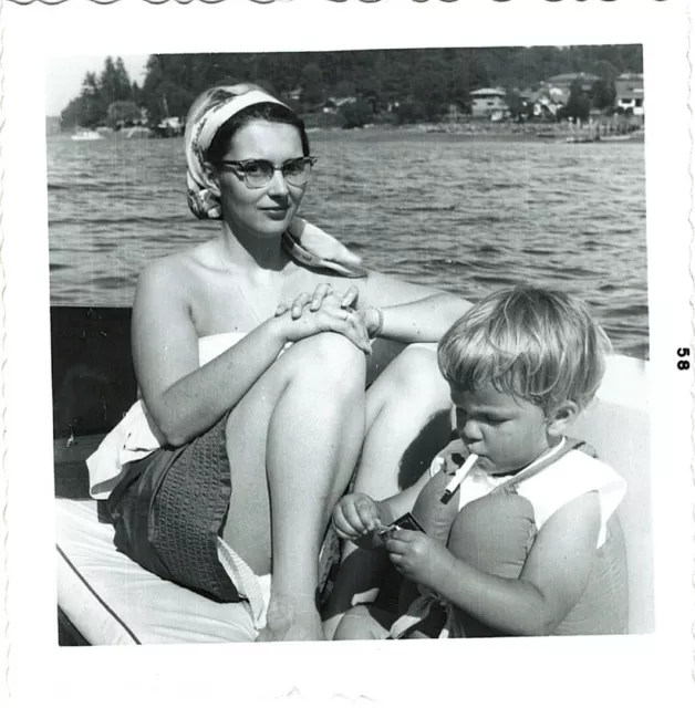 Vintage Photograph Young Boy lighting up a cigarette next to mom on a boat 1958