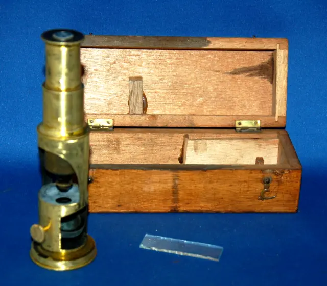 A 19th century drum type brass microscope, single attached lens, box, slide