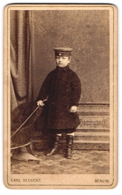 Fotografie Carl Seegert, Berlin, Knabe mit Mantel und Krätzchen als Soldat