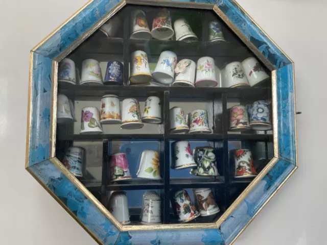 Set of 33 ceramic thimbles in blue wall box , glass door.  Flowers various.