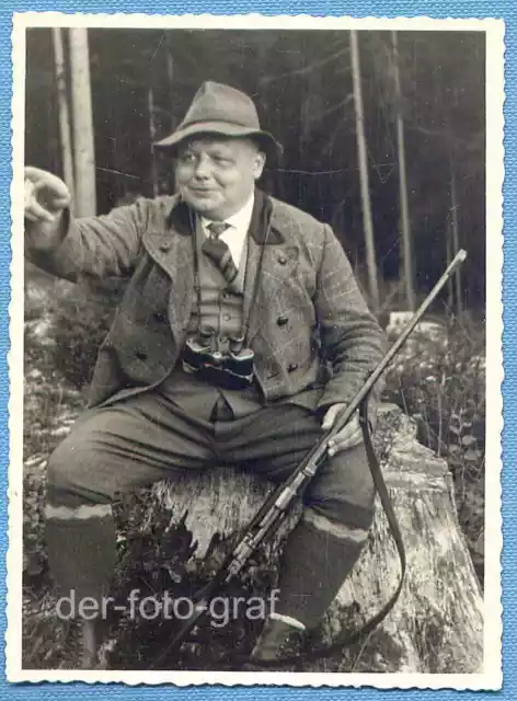 Foto, Jäger in Jagdkleidung mit Gewehr und Fernglas auf einem Baumstamm, um 1931