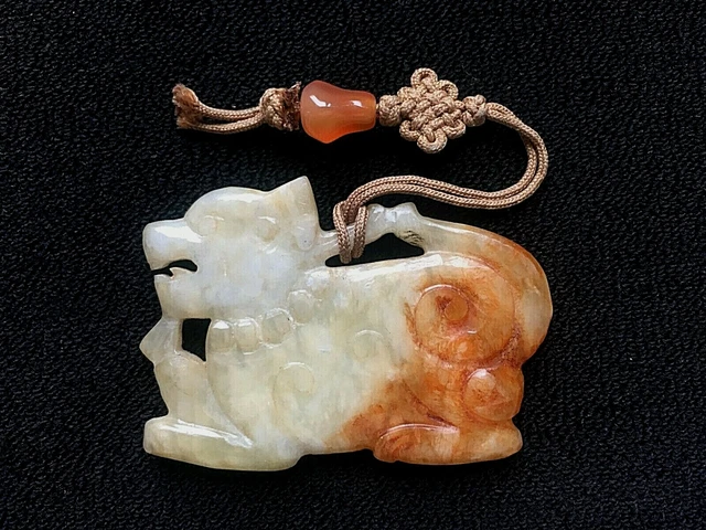 A Chinese celadon and russet jade pendant, 19th/20th century hand carved Foo Dog
