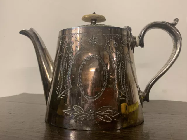 An Antique Silver Plated Tea Pot With Elegant Engraved Patterns.