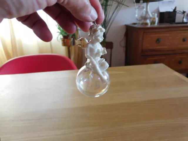 Décoration de sapin angelot assis sur une boule en verre à suspendre