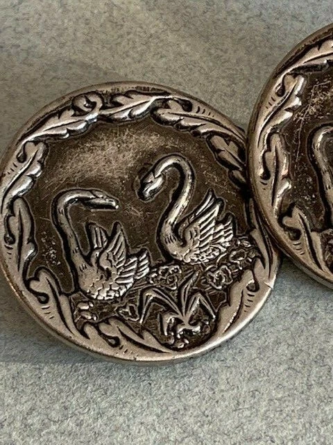 Deux anciens boutons, en métal blanc, représentent des cygnes, décor amoureux