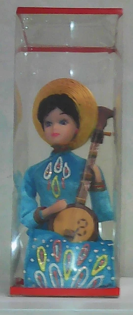 Poupée vietnamienne en costume traditionnel joue de l’instrument de musique
