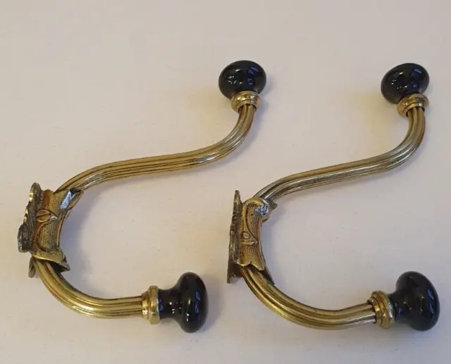 Pair of antique brass coat/hat hooks with black porcelain knobs.