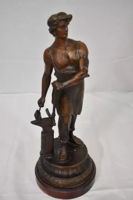 Metal Sculpture Of Blacksmith On A Wooden Plinth.